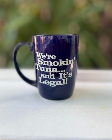 Navy blue mug with white text on a blurred green background